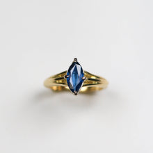 This remarkable piece features a 2.5mm wide band, intricately hand-carved from luxurious 18ct yellow gold. The band is adorned with a delicate vine design, symbolising the natural beauty and elegance that define Jeremy Hoye's jewellery. At its heart lies a stunning 1.25ct marquise blue sapphire, set to capture and reflect light beautifully.