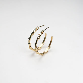 Crafted in luxurious 9ct gold, they measure approximately 25mm in diameter, striking a balance between bold presence and delicate elegance. The signature-wrapped vine design adds a touch of organic beauty, making these hoops uniquely distinctive. 