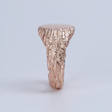 This remarkable piece, crafted from 9ct rose gold, features intricate hand-carved feather details that wrap around the band, creating a unique and captivating texture. The oval face of the ring provides ample space for personalisation, allowing you to add a custom-engraved family crest or initials, making it a truly bespoke piece.