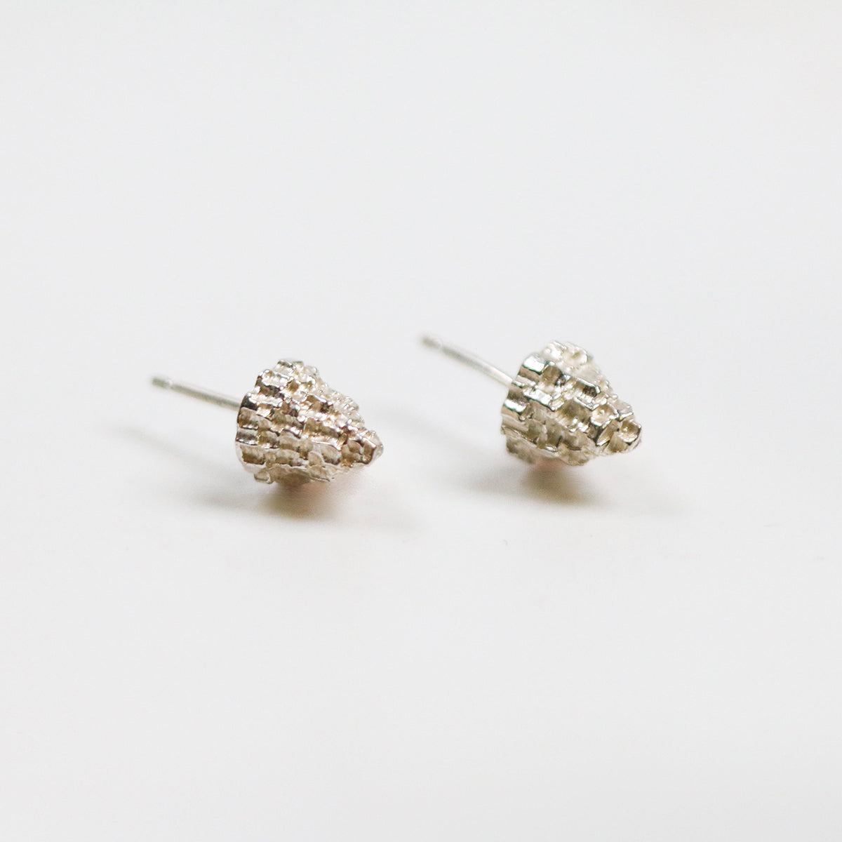 These Cone Lunas come in a silver finish. These textured studs measure 7mm wide and 8mm in length.