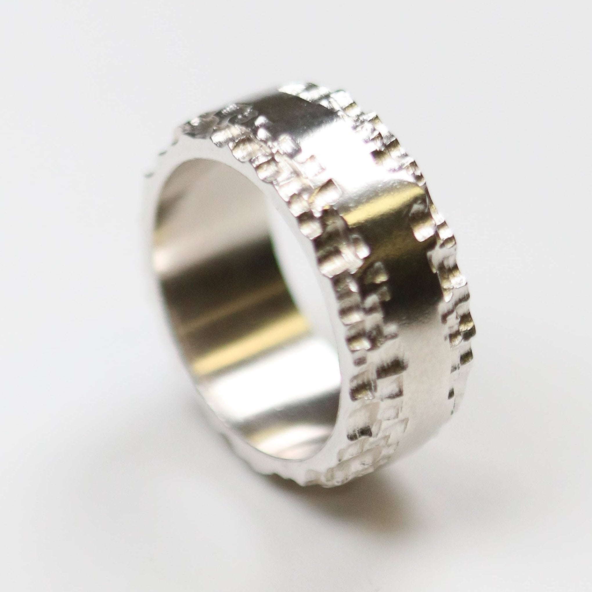 This silver band measures 10mm in width, and features a flat centre with contrasting textured edge.