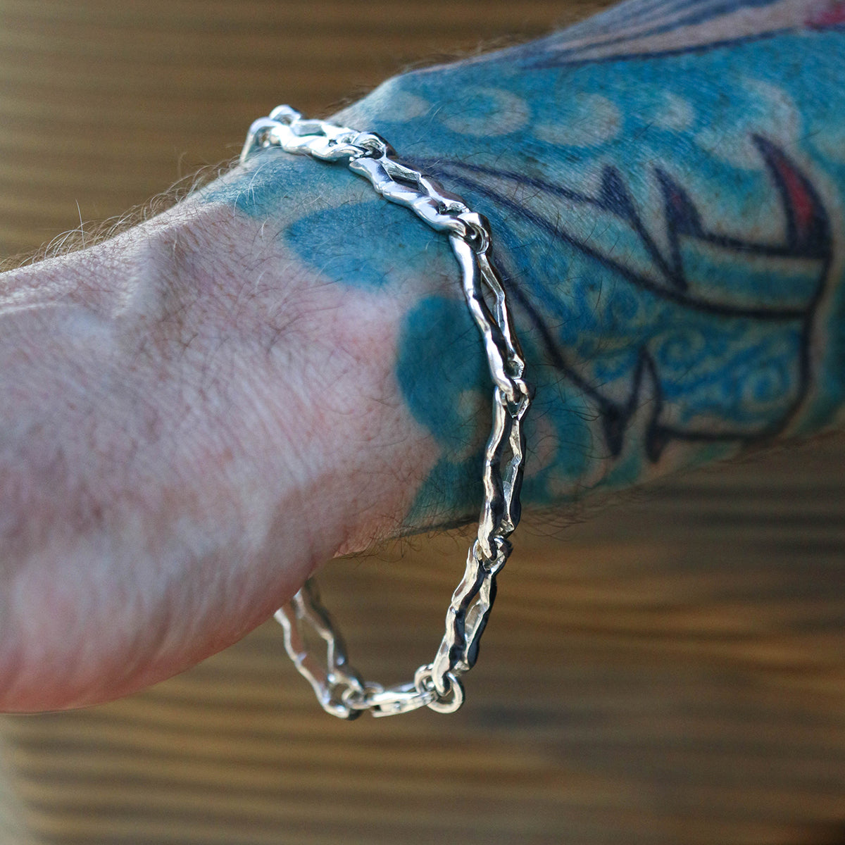 Carved silver long link bracelet on a man's wrist