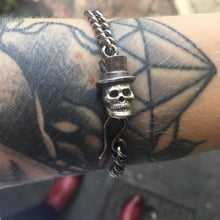 Silver curb link bracelet chain with silver skull in top hat fastening. Measurements are 7 1/4 inches for women and 8 1/2 inches for men.