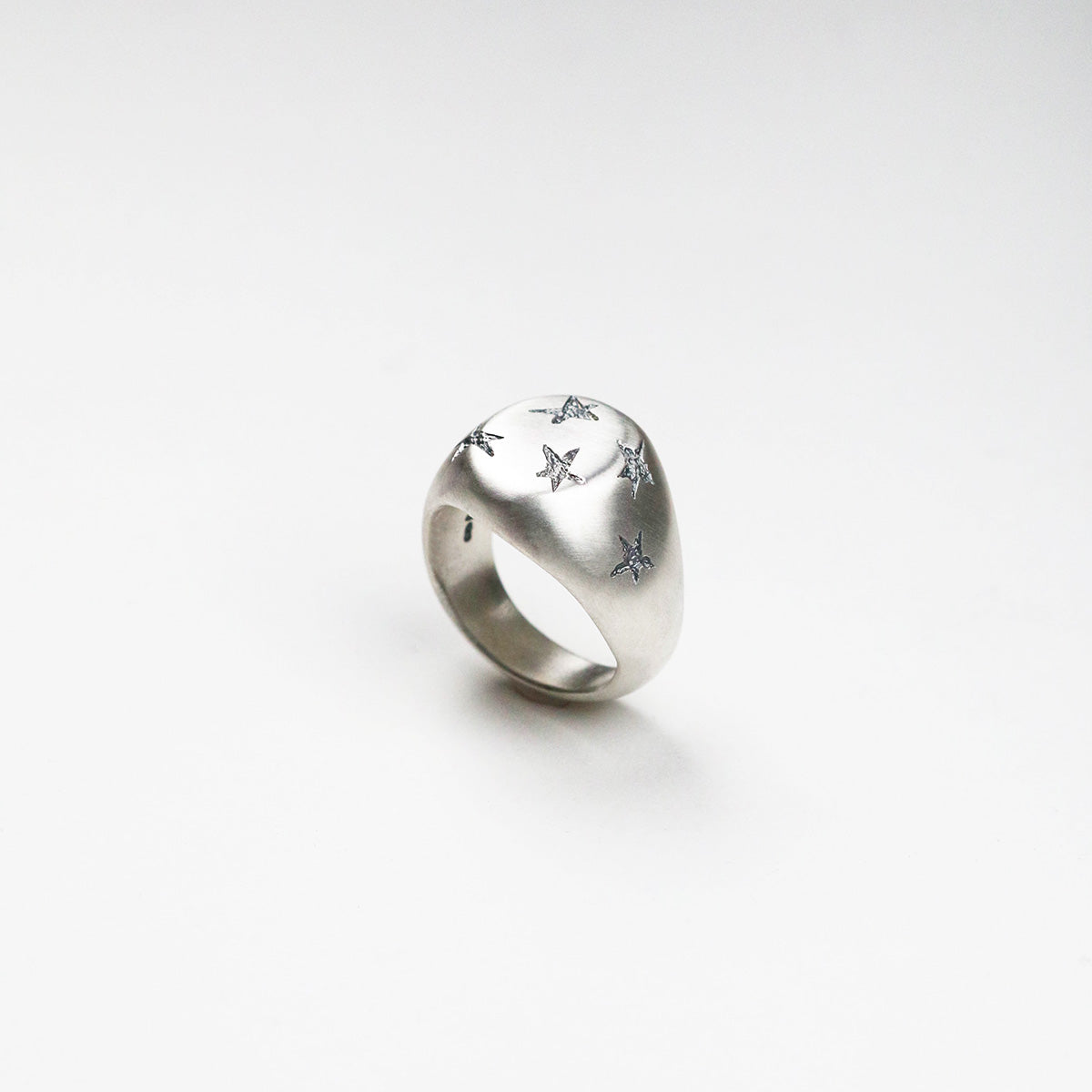 Handmade in silver with scattered inlaid textured star shapes, this ring is designed as an alternative to the traditional style signet ring. the top measures 17mm by 14mm.