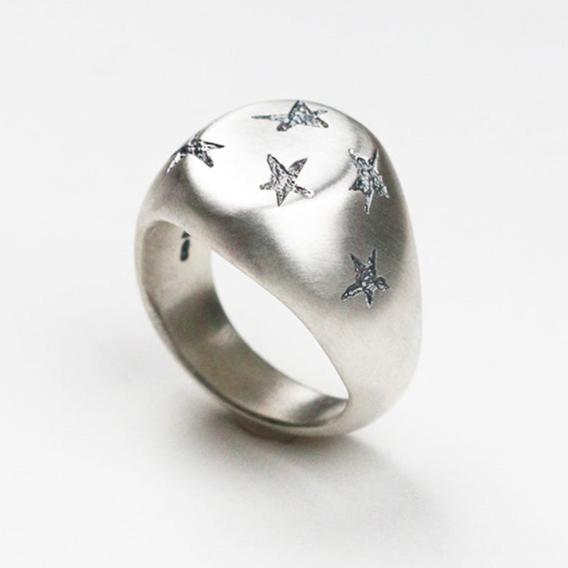 Handmade in silver with scattered inlaid textured star shapes, this ring is designed as an alternative to the traditional style signet ring. the top measures 17mm by 14mm.