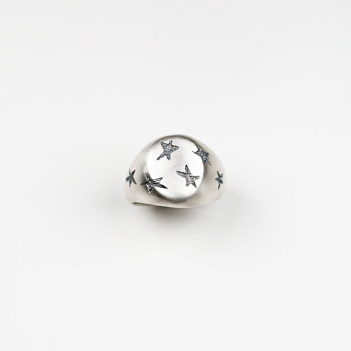 Handmade in silver with scattered inlaid textured star shapes, this ring is designed as an alternative to the traditional style signet ring. the top measures 17mm by 14mm.