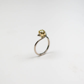 An 18ct white gold simple fine band with contrasting four petal setting in 18ct yellow gold. Set with a natural yellow .51pt round, brilliant cut diamond. 